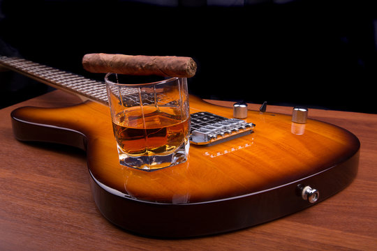 Glass of rum and plectrum on the electric guitar