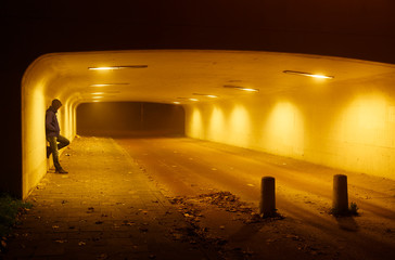 Gangster leaning against the wall of a tunnel.
