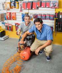 Father And Son Holding Air Compressor In Store