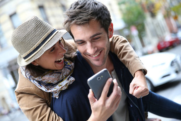 Cheerful couple having fun playing with smartphone