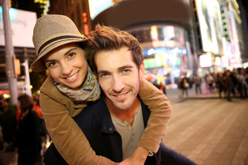Couple standing in Time Square quarter by night