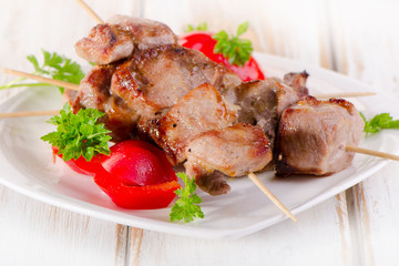 Kebabs served with vegetables on a  white plate
