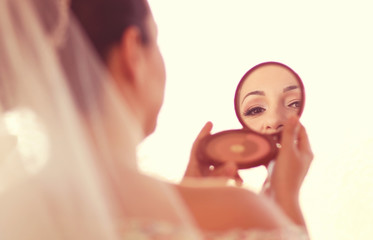Bride looking in a small mirror
