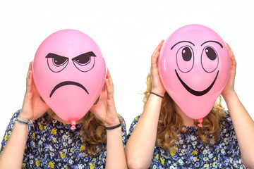 Two girls holding pink balloons with facial expressions
