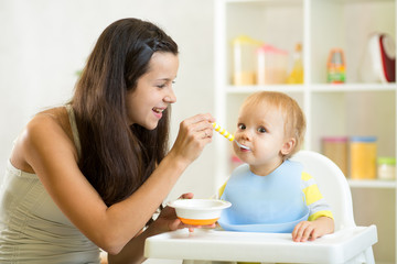 Obraz na płótnie Canvas Mother spoon-feeding her baby