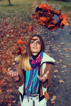 Young Woman Throwing Leaves In The Air