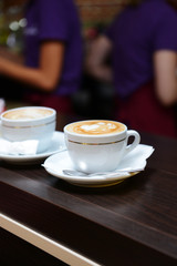 Cups of coffee with cute drawing in cafe