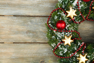 Green Christmas wreath with decorations on wooden background