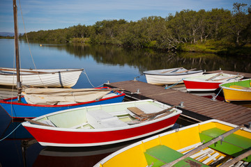 Fototapeta na wymiar Color Wooden Boats with Paddles in a Lake