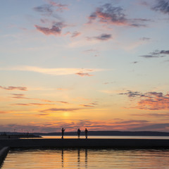 People silhouettes on lake quay in evening