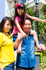 Asian family with child standing in front of home