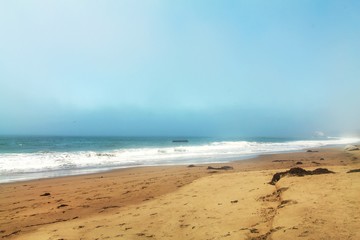 Beach wave sand and foggy sky