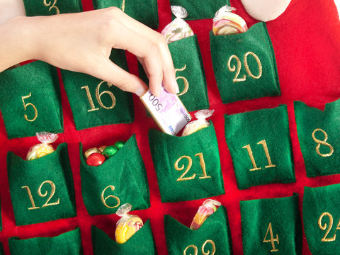 Mutterhand hält eine Schokoladen 500 Euro Spielgeld aus dem Adventskalender voller Geschenke