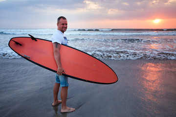 Surfer walking on coast in Bali