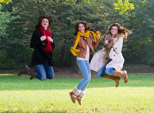 Three young women jumping joyfully in the park