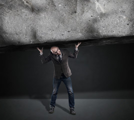 man with glasses holding a block of stone