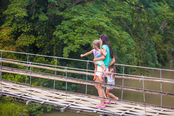 Young mother with her little girls on suspension bridge over the