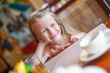 Adorable little girl having breakfast at resort restaurant