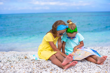 Little adorable girls with big map on tropical beach vacation