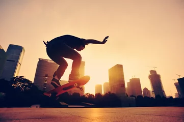 Afwasbaar fotobehang vrouw skateboarder skateboarden bij zonsopgang stad © lzf
