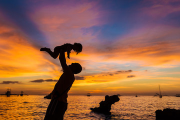 Fototapeta premium silhouettes of father and child on sunset sea background