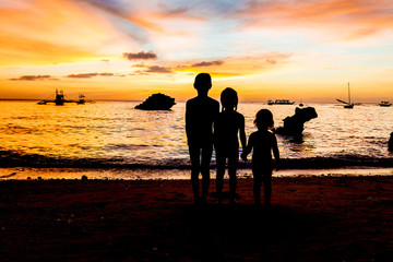 Fototapeta na wymiar three kid silhouettes on sunset sea background