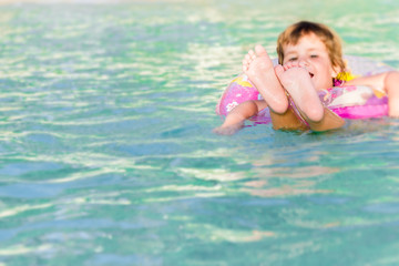young happy child swimming in the sea in a floating ring on trop