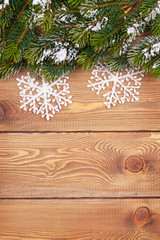 Christmas fir tree with snow and snowflake decor on rustic woode