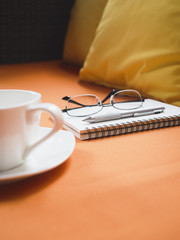 Close up Pen and book with eyeglasses coffee on sofa