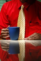 Man in red long sleeve shirt, yellow necktie, holding coffee mug