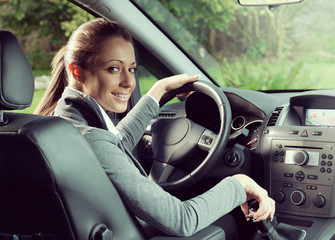 Smiling woman driving and looking at camera