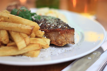 Piece of steak with french fries close-up.
