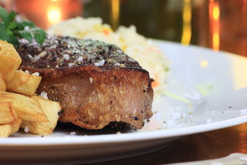 Piece of steak with chips on a plate.