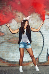 Naughty girl in pink rabbit ears with red smoke bombs