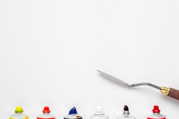 palette knife and oil paint tubes on white canvas