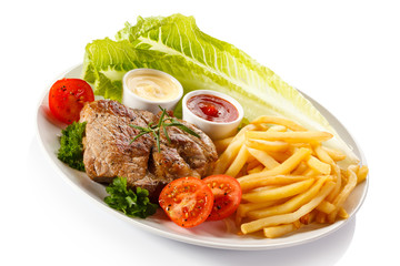 Barbecued steak, French fries and vegetables