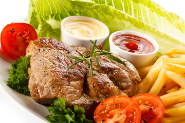 Barbecued steak, French fries and vegetables