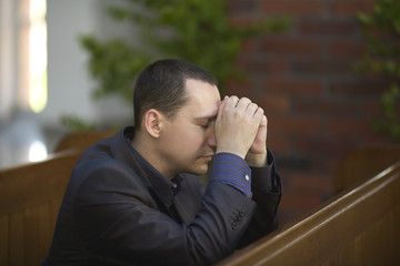 Handsome young man praying in a church