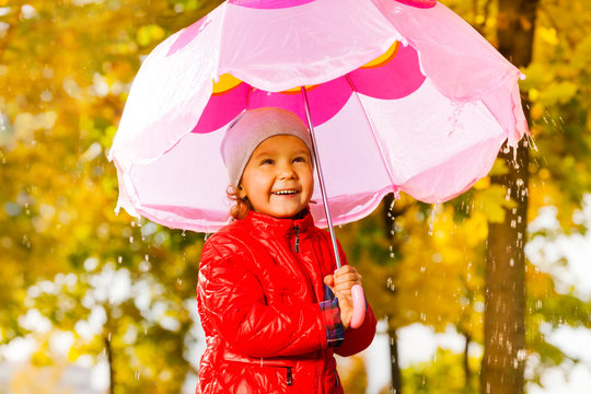 Positive girl with umbrella standing under rain