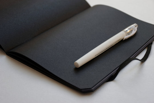 Notebook with black paper and white pen opened