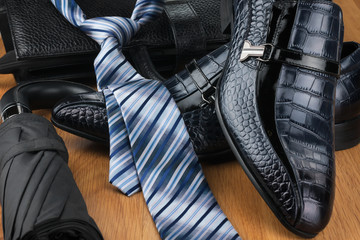 Classic men's shoes, tie, umbrella and bag on the wooden floor