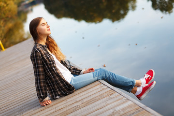 Young beautiful girl sitting on a pier