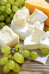 Cheese Assortment with grapes on a wooden background