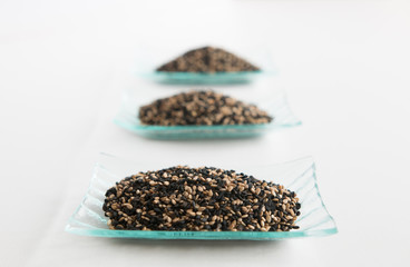 Three little trays of black and white sesame seeds