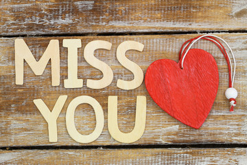 "Miss you" written with wooden letters next to red wooden heart