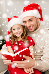 smiling father and girl in santa hats reading book