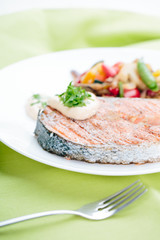 Grilled Salmon with Fresh vegetables on green background