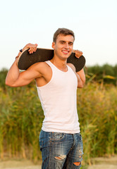 Fototapeta premium smiling teenage boy with skateboard outdoors