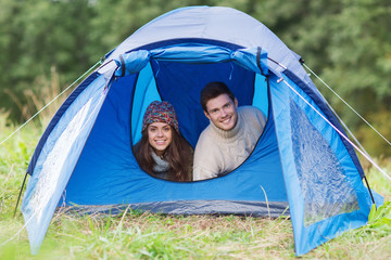 smiling couple of tourists looking out from tent