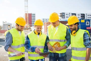 group of smiling builders with tablet pc outdoors